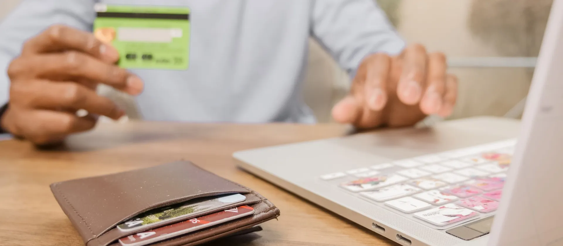 Hands holding a payment card beside a laptop.