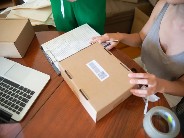 A small-business owner preparing a parcel for fulfilment.