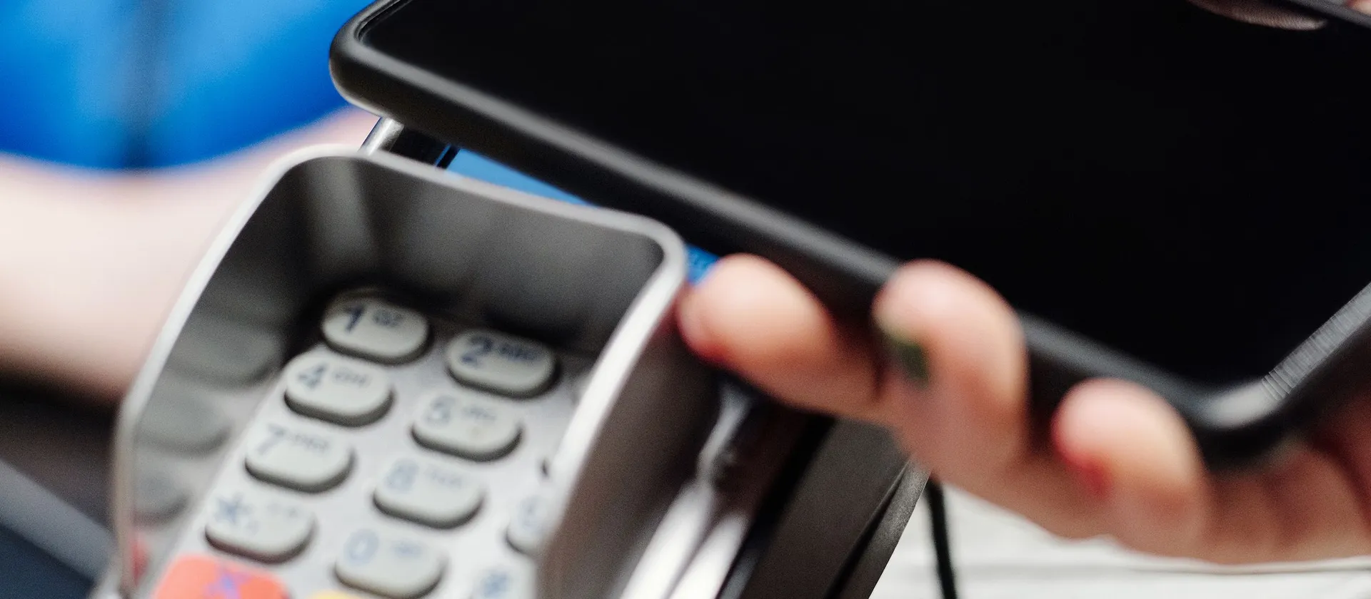 A smartphone held above a contactless payment terminal.