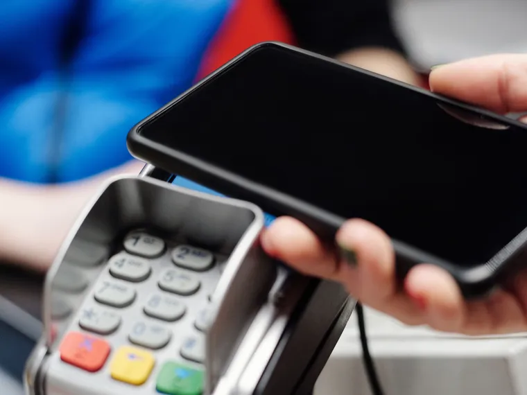 A smartphone held above a contactless payment terminal.