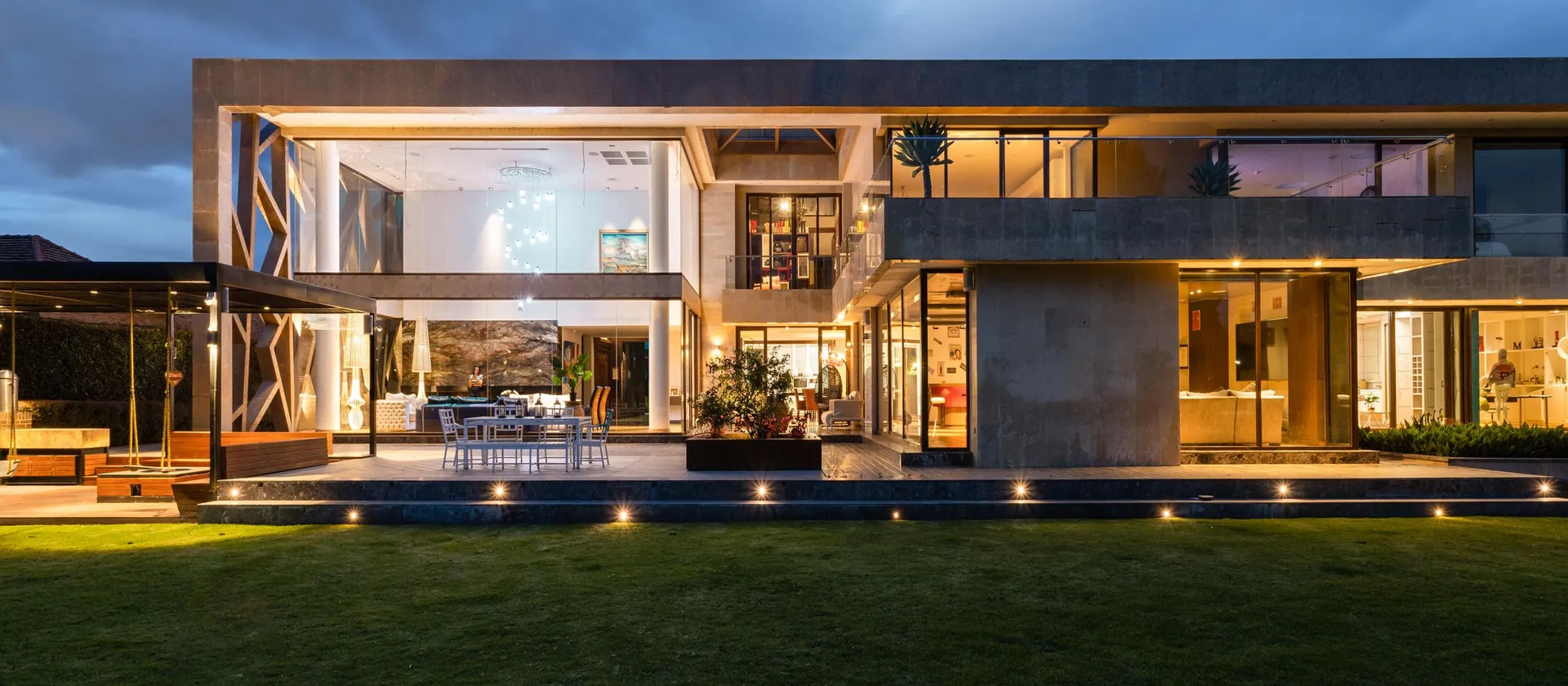 The full facade of a modern residential property illuminated at dusk.