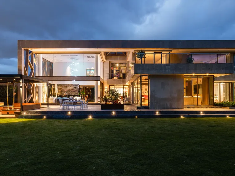The full facade of a modern residential property illuminated at dusk.